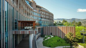 A modern building with a curved facade, large windows, and a landscaped courtyard. - Paragraph Golf & Spa Tabori, Autograph Collection (Tbilisi)