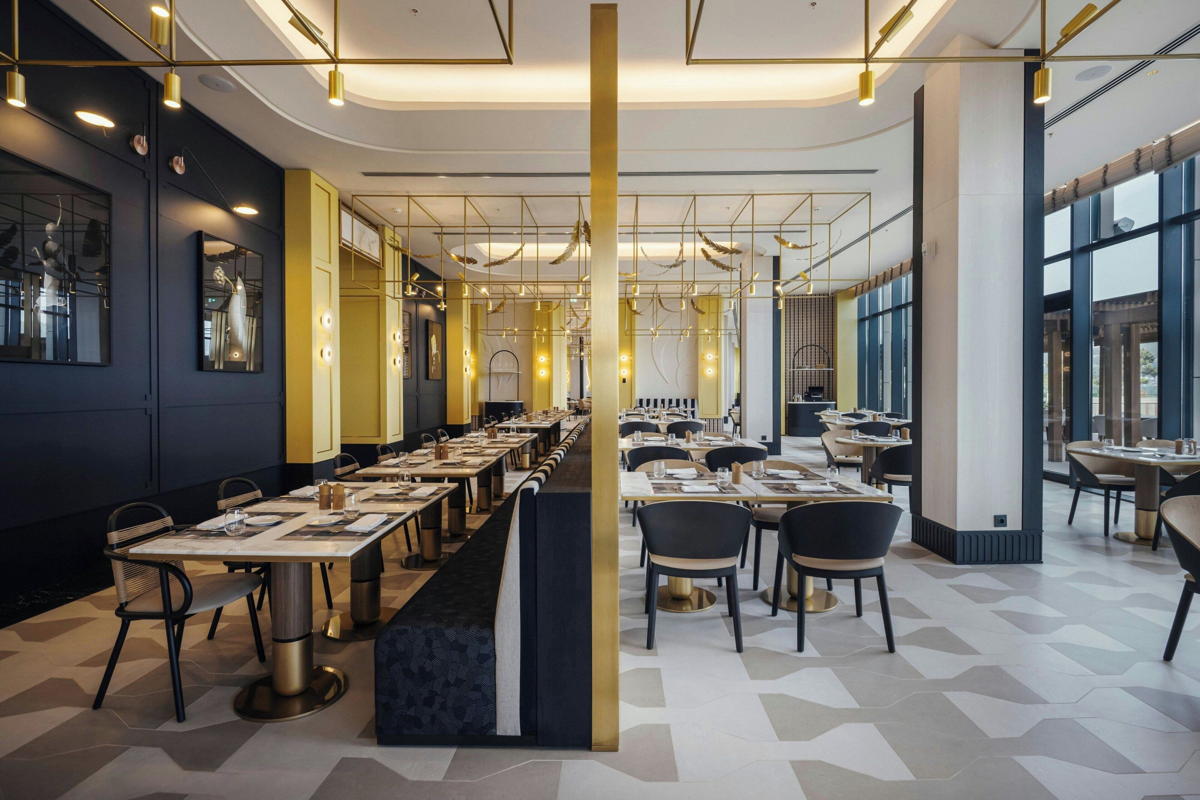 A modern restaurant with a long counter, multiple tables, and chairs.