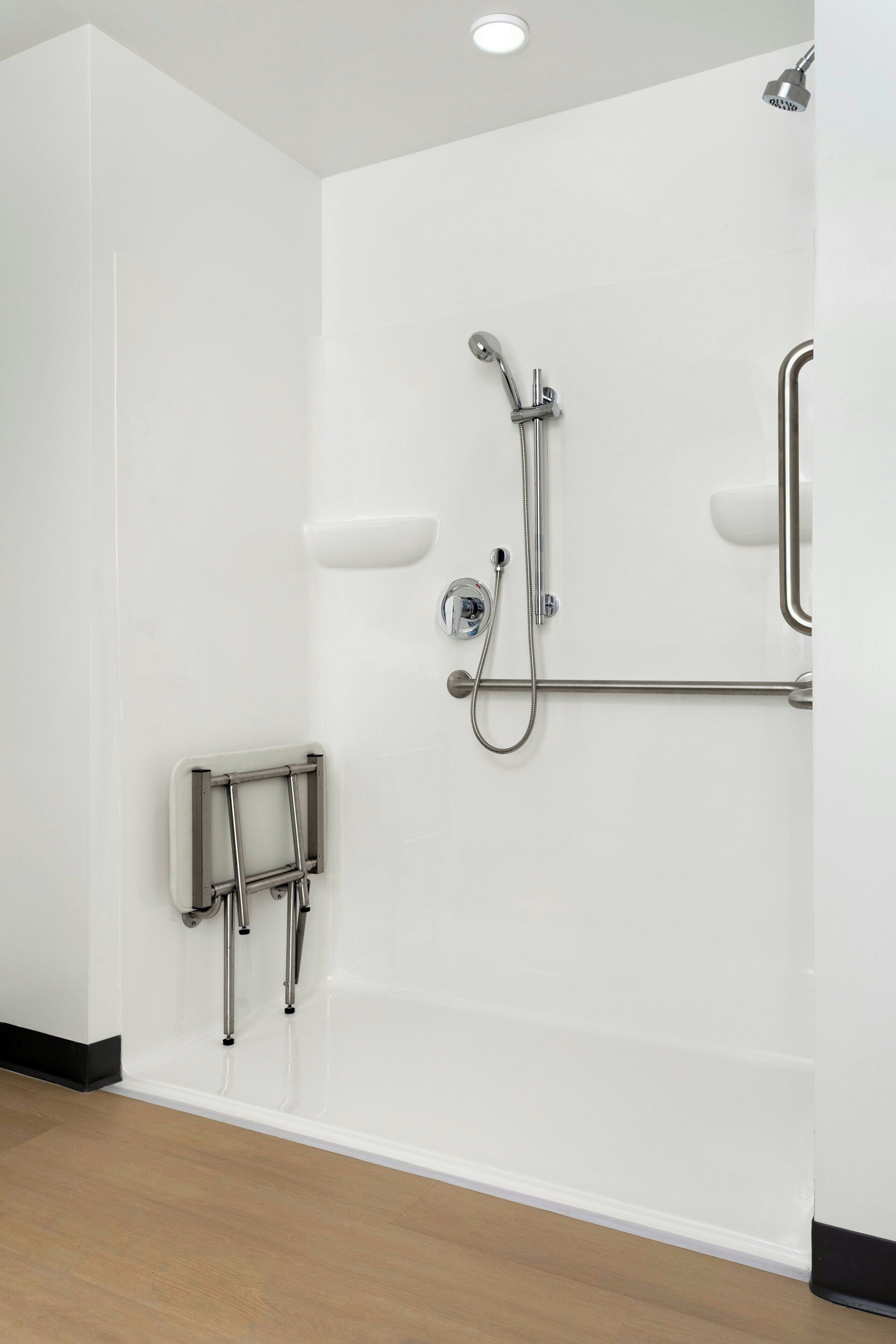 Een moderne badkamer met een douche, grepen en een handrail.