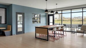 A modern kitchen with a central island, bar stools, and large windows offering a view of the outdoors.