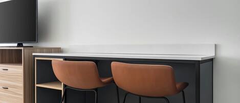 A modern bar area with two stools, a flat-screen TV, and a wooden cabinet.