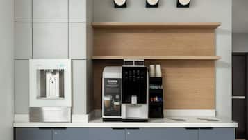Una cocina moderna con cafetera integrada, refrigerador y microondas.