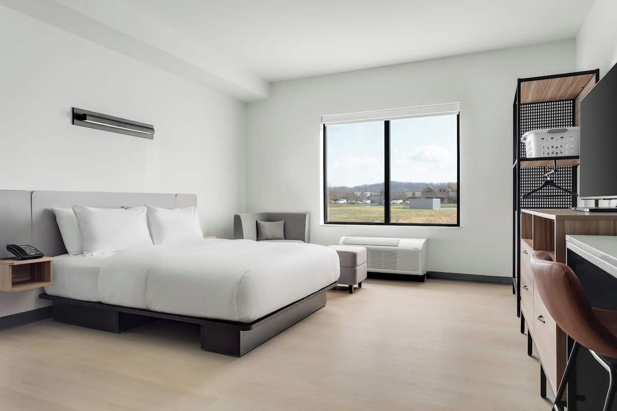 A modern bedroom with a bed, bedside table, and a large window.
