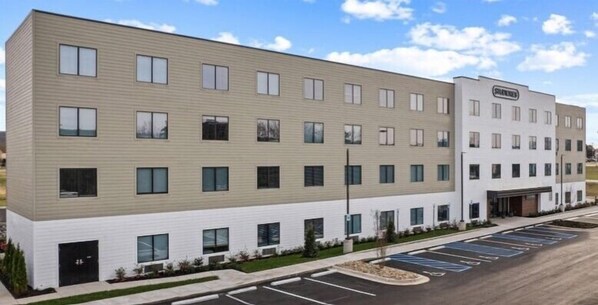 A multi-story building with a flat facade, large windows, and a parking lot in front.