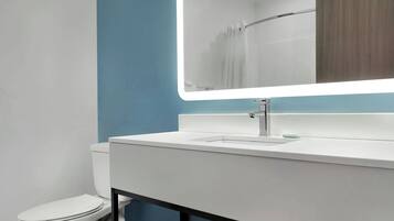 Une salle de bain moderne avec un lavabo blanc, un miroir et des toilettes.