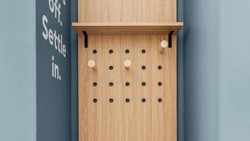 Un coin avec un mur sur lequel est fixé un porte-chaussures en bois et une étagère, et un autre mur sur lequel on peut lire : « Enlevez vos chaussures. Installez-vous confortablement. »