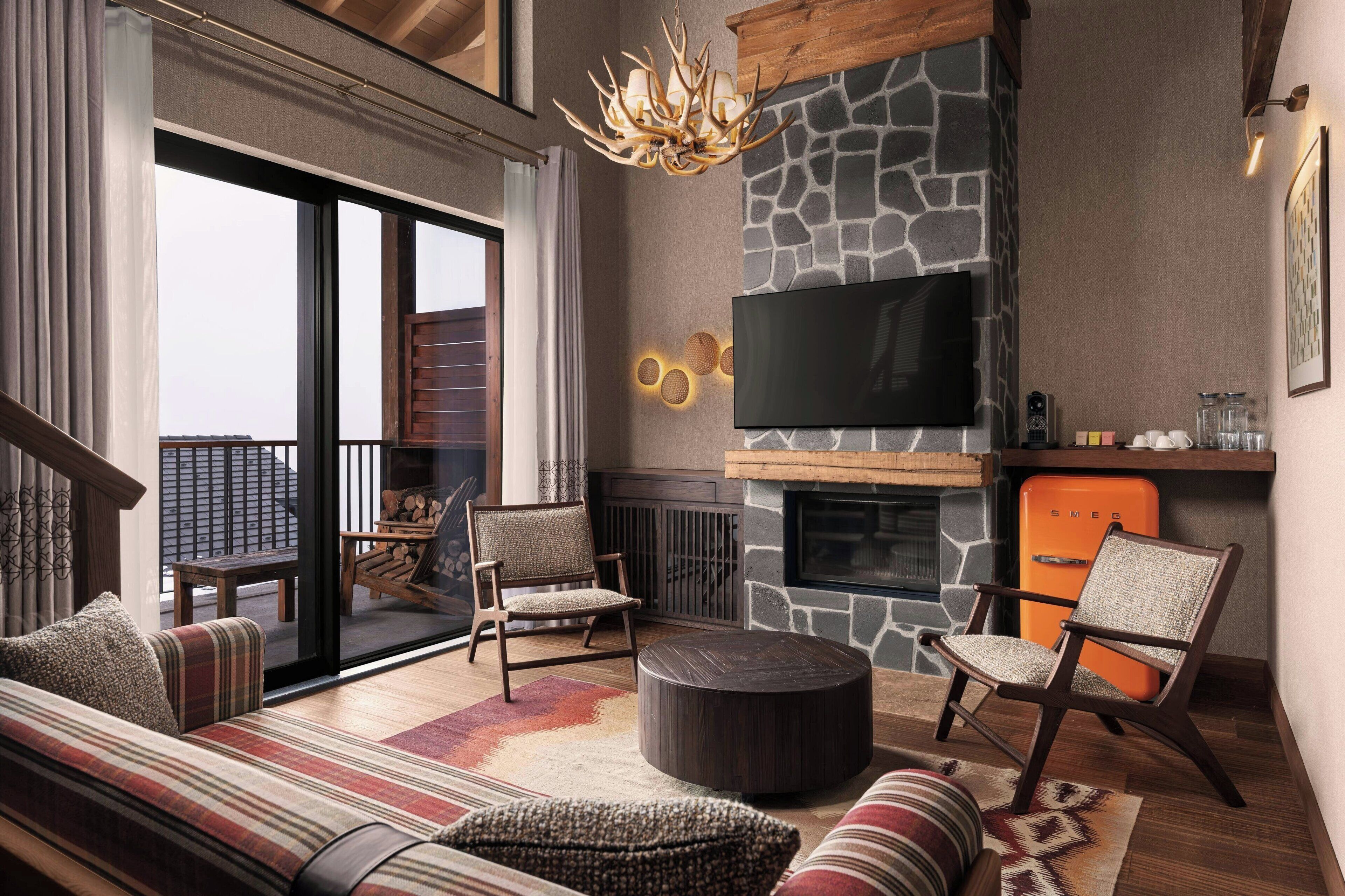 A modern living room with a stone fireplace, a flat-screen TV, and comfortable seating.