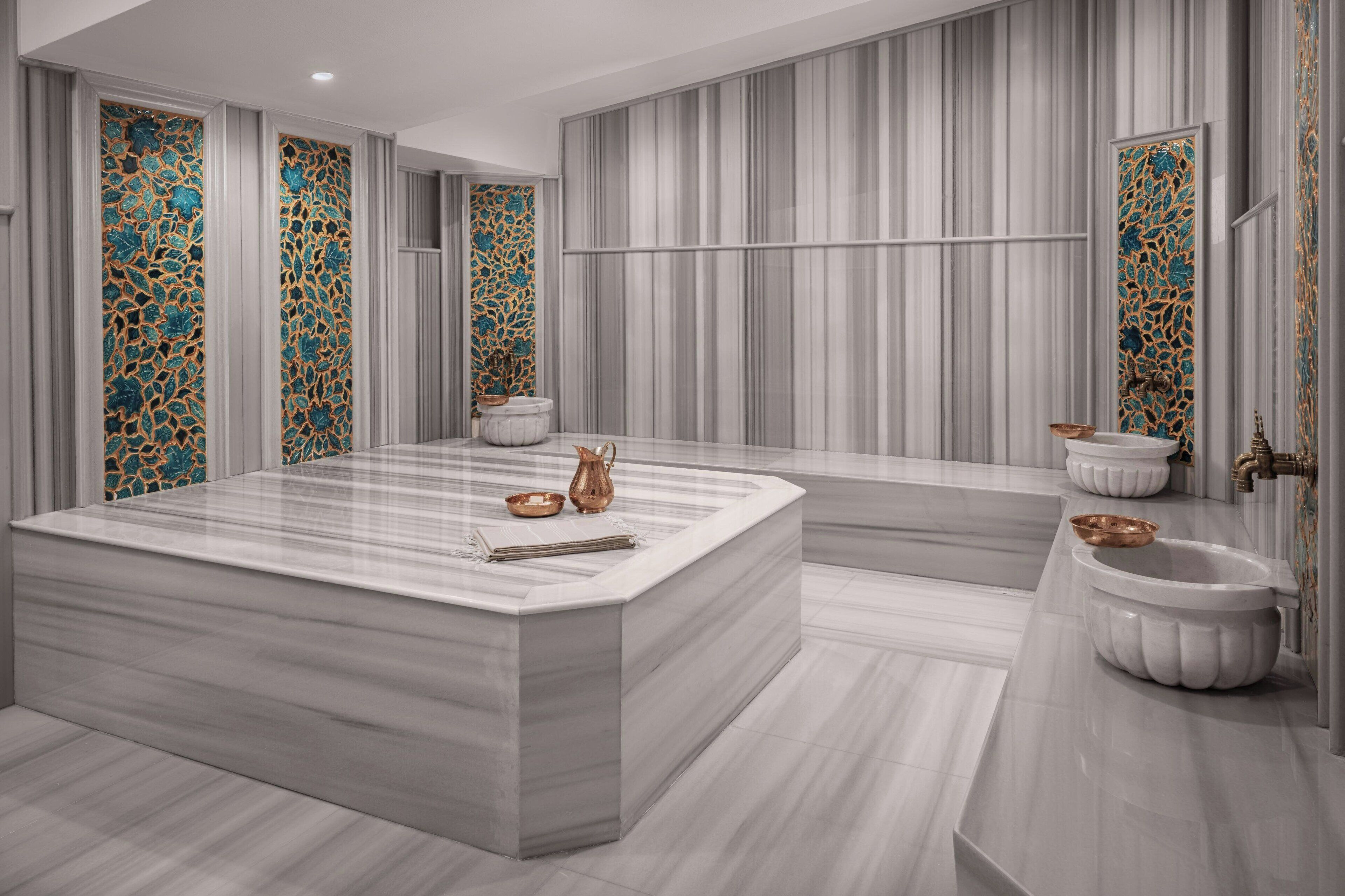 A modern bathroom with a large marble sink, two wall-mounted basins, and decorative tiles.