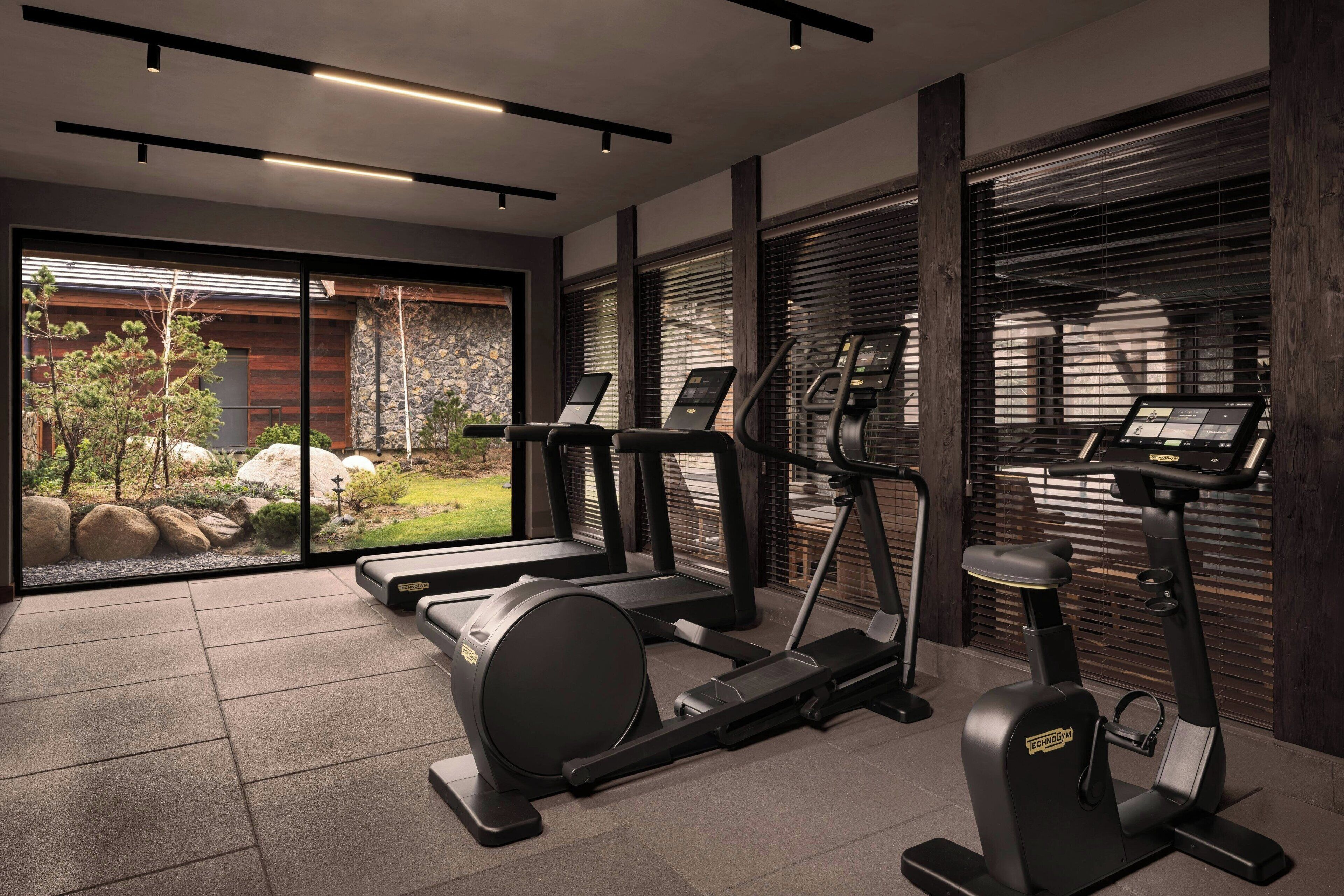 Un gimnasio moderno con cintas de correr, elípticas y una bicicleta estática.