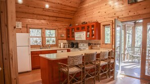 A wooden cabin kitchen with a central island, bar stools, and a refrigerator. - Splendor Mountain Ruby Cabin (Tiger)