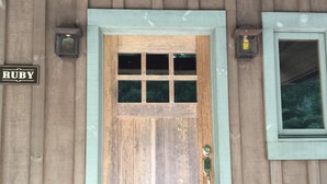 A wooden door with a grid pattern window, a doorbell, and two wall-mounted lights. - Splendor Mountain Ruby Cabin (Tiger)