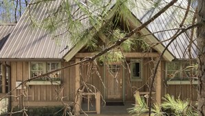 A rustic wooden cabin with a metal roof, a front porch, and a small garden area. - Splendor Mountain Ruby Cabin (Tiger)