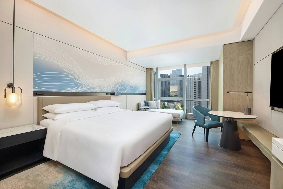 Une chambre d’hôtel moderne équipée d’un grand lit, d’un bureau, d’une chaise et d’un téléviseur.