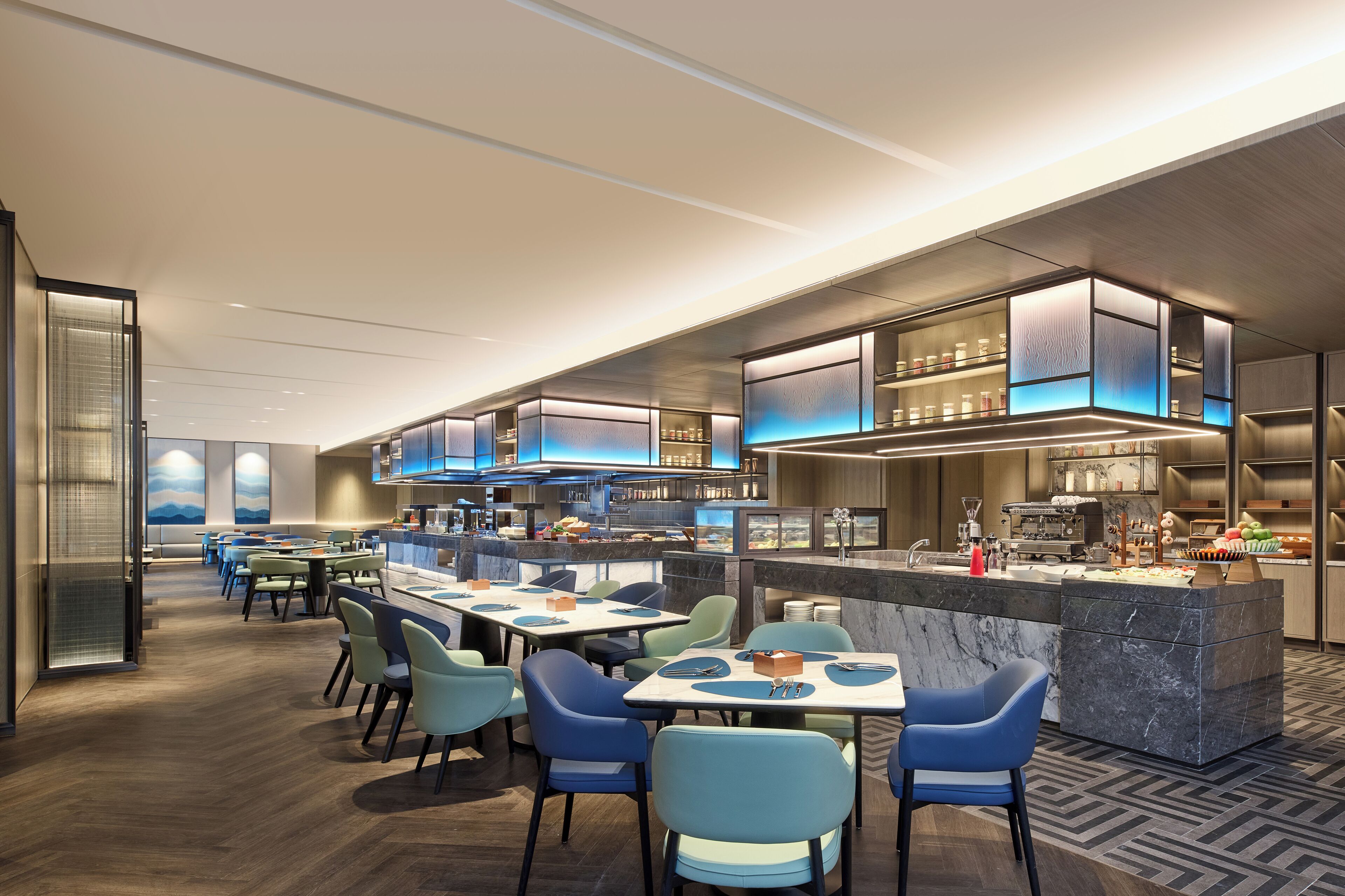 A modern restaurant with a central bar area, multiple dining tables with chairs, and a view of the cityscape through large windows.