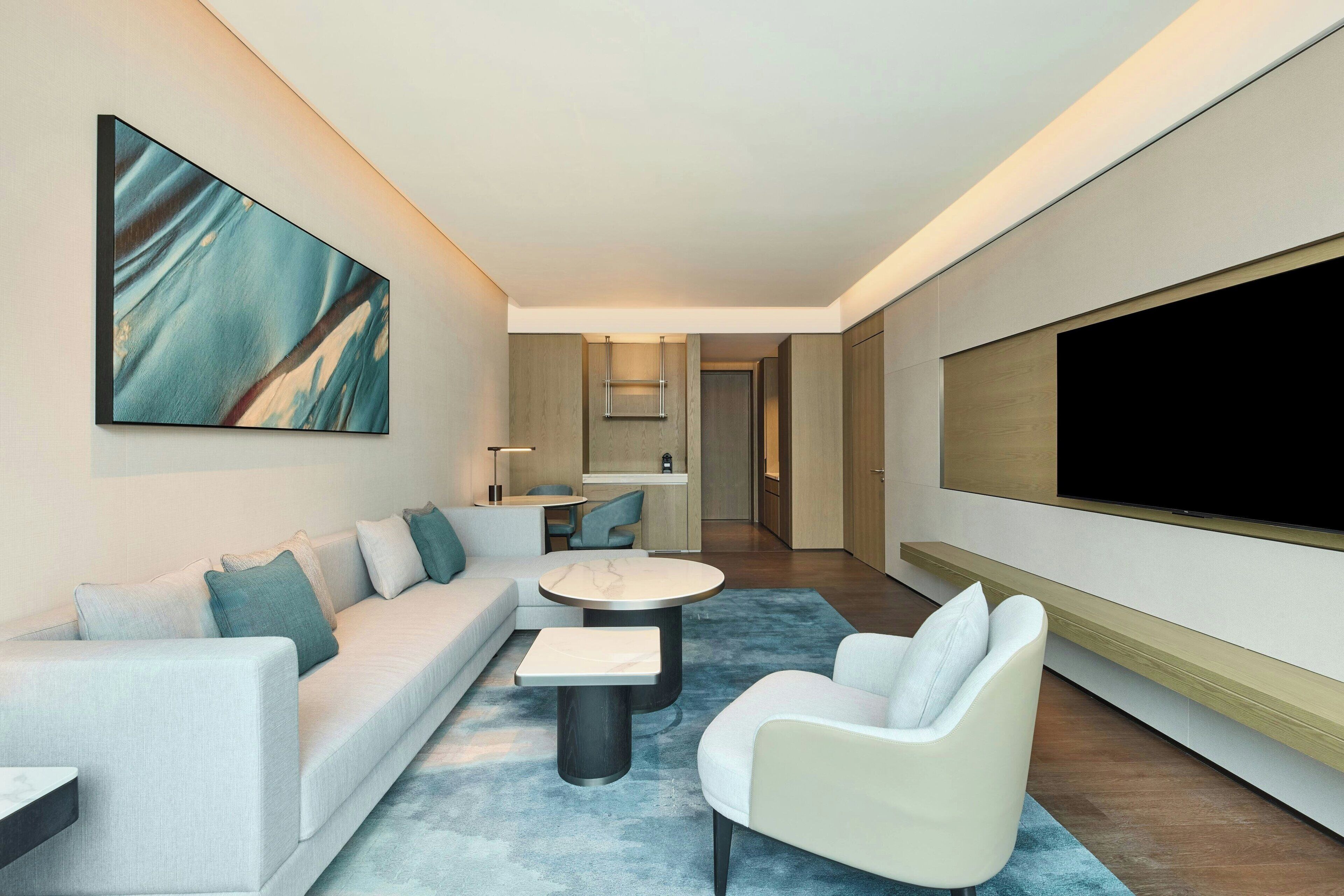 A modern living room with a sofa, armchairs, a coffee table, and a flat-screen TV.