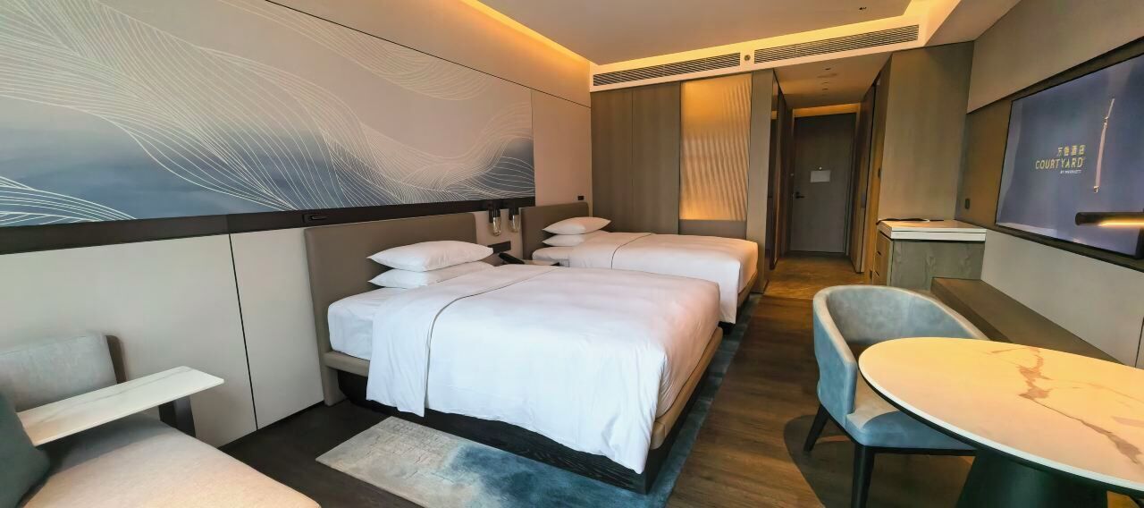 A hotel room with a large bed, a desk, and a TV.