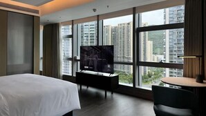 Une chambre d’hôtel avec un grand lit, une télévision, un bureau et une vue sur les immeubles de grande hauteur.