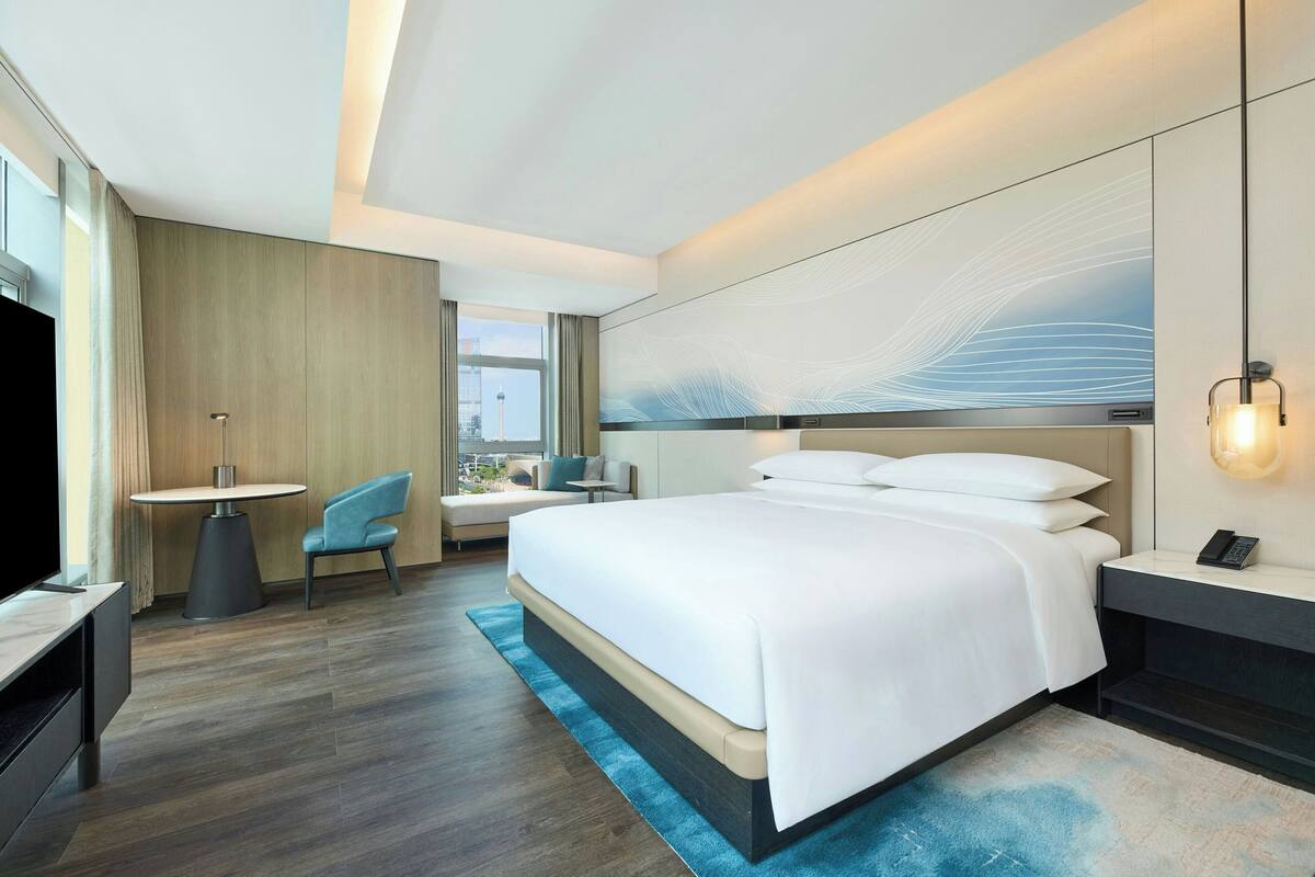 Une chambre d’hôtel moderne équipée d’un grand lit, d’un bureau, d’une chaise et d’un téléviseur.