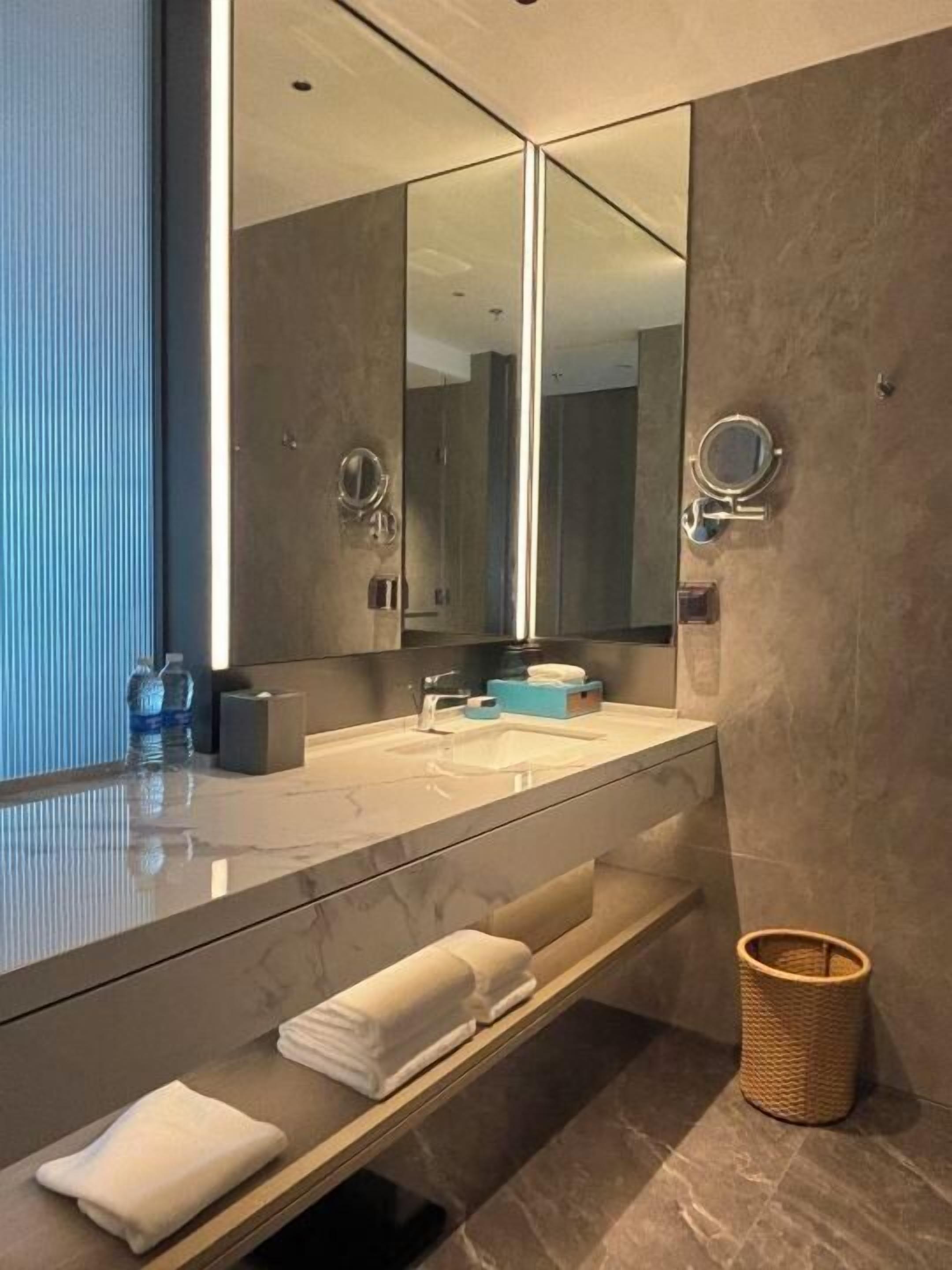 A modern bathroom with a large mirror, a sink, and a towel rack.