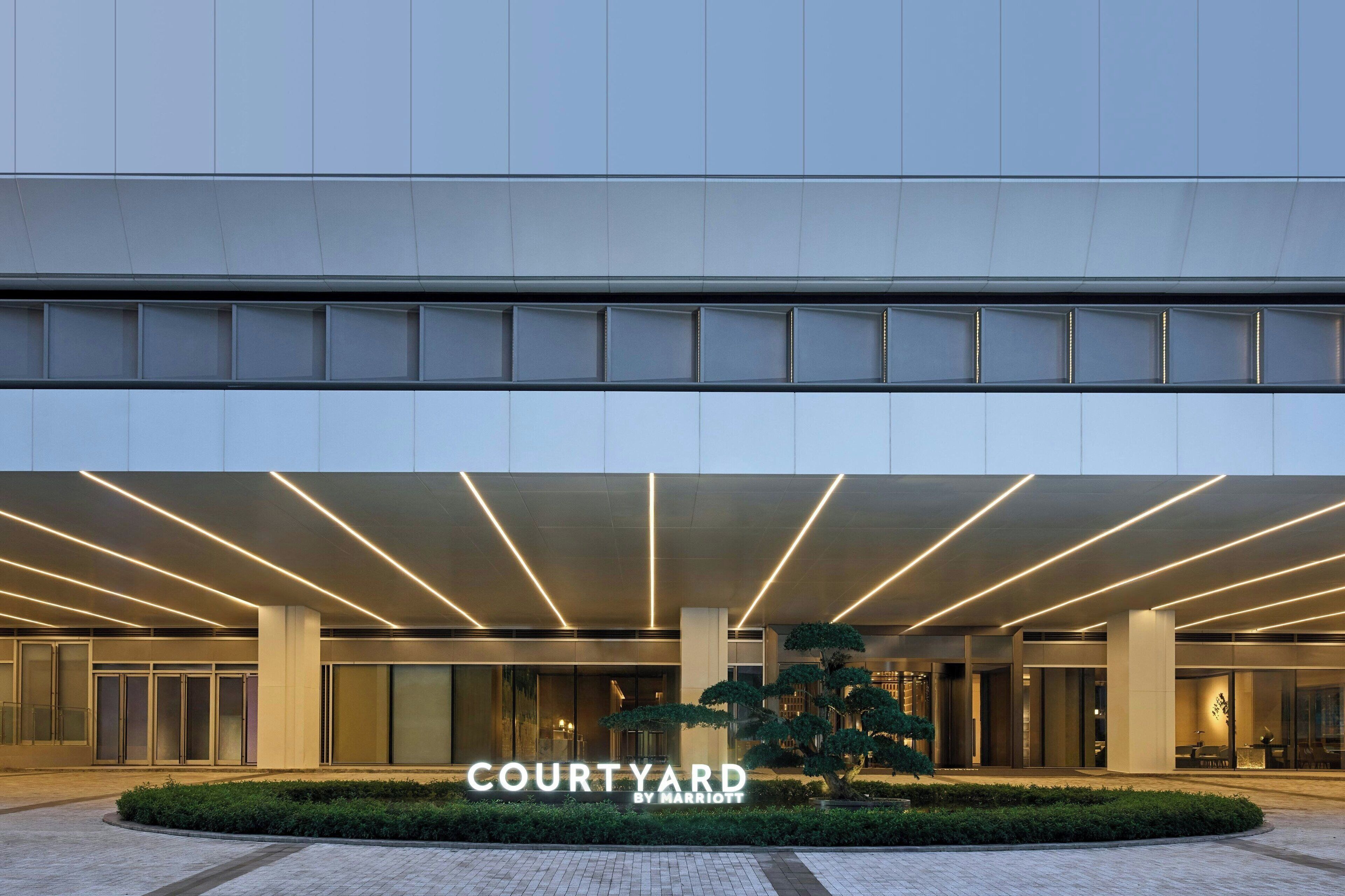 A modern hotel entrance with a large sign reading "COURTYARD BY MARRIOTT".