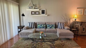 Un salon avec un canapé, une table basse en verre, une lampe et une cheminée.