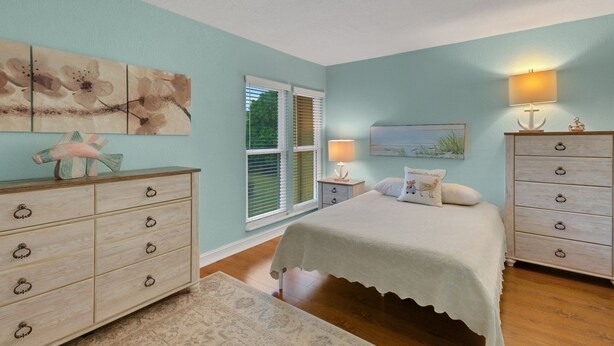 Une chambre à coucher comprenant un lit, une commode, une table de chevet et des œuvres d’art accrochées aux murs.