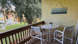 Un balcon avec une petite table et deux chaises, une clôture en bois et une pancarte sur laquelle on peut lire « RELAX ».