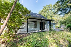 A modern house with a covered porch, surrounded by trees and grass.