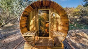 Une cabane en bois à la forme circulaire, dotée d’une porte centrale et de bancs à l’intérieur.