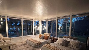 Une chambre avec une grande fenêtre, un lit, une chaise et un plancher en bois.