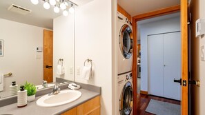 Une salle de bain équipée d’un lavabo, d’un miroir, d’un porte-serviettes et d’un lave-linge.