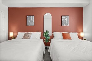 Ein Hotelzimmer mit zwei Betten, einem großen Spiegel und Bildern an den Wänden.