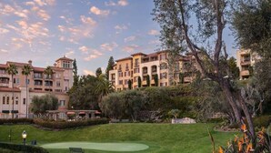 A golf course with a well-maintained lawn, a putting green, and a sand bunker.