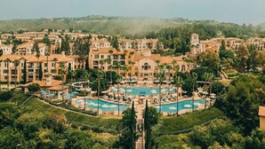 A resort with multiple buildings, a central pool area, and surrounding greenery.