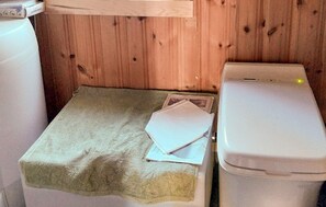 A small, compact bathroom with a wooden wall, a white toilet, and a small sink.