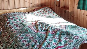 A wooden room with a bed covered by a patterned blanket. - 3 bedroom beautiful home in Tynset (Tynset)