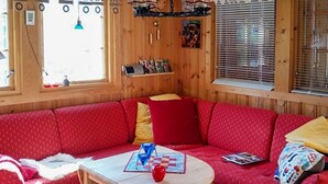 A cozy room with a red sofa, a small table, and a window with blinds. - 3 bedroom beautiful home in Tynset (Tynset)