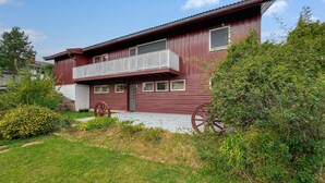 Ein zweistöckiges Holzhaus mit Balkon, Veranda und einem großen Wagenrad.
