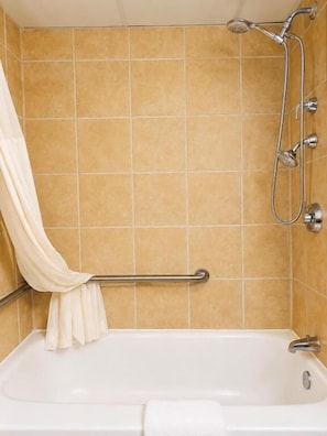 Ein Badezimmer mit Badewanne, Dusche und Handläufe.