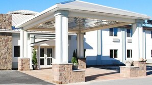 Un edificio con entrada cubierta, pilares de piedra y cielo despejado.