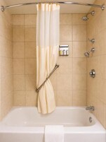 Ducha con cortina, cabezal de ducha manual, boquilla de masaje manual y dispensador de jabón de pared.