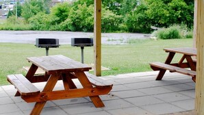Una mesa de picnic con un banco de madera, un poste metálico y un cubo de basura.