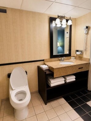 A bathroom with a toilet, sink, mirror, and towel rack. - Travel Inn (Watertown)