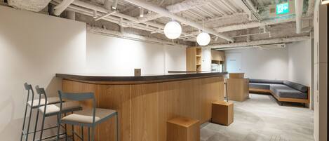 A modern office space with a curved reception desk, bar stools, a wooden bench, and a sofa.