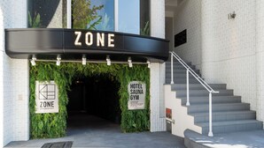 A hotel entrance with a sign reading "ZONE HOTEL SAUNA GYM" and a staircase leading inside. - ZONE SHINSAIBASHI WEST (Osaka)
