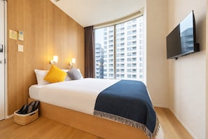 A hotel room with a bed, a TV mounted on the wall, a window with a view of a building, and a shoe rack. - unito OSAKA Shinsaibashi West (Osaka)