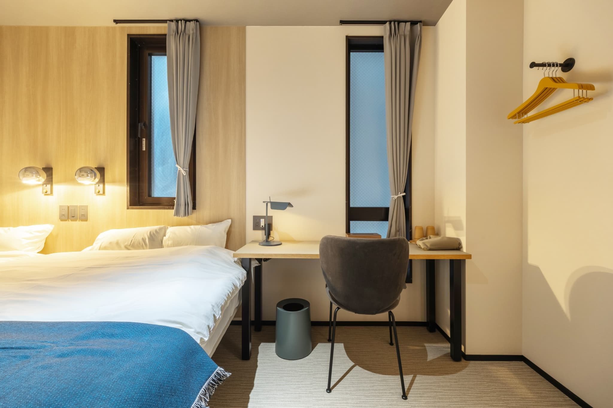 Une chambre d’hôtel avec un lit, un bureau, une chaise et une fenêtre avec des rideaux.