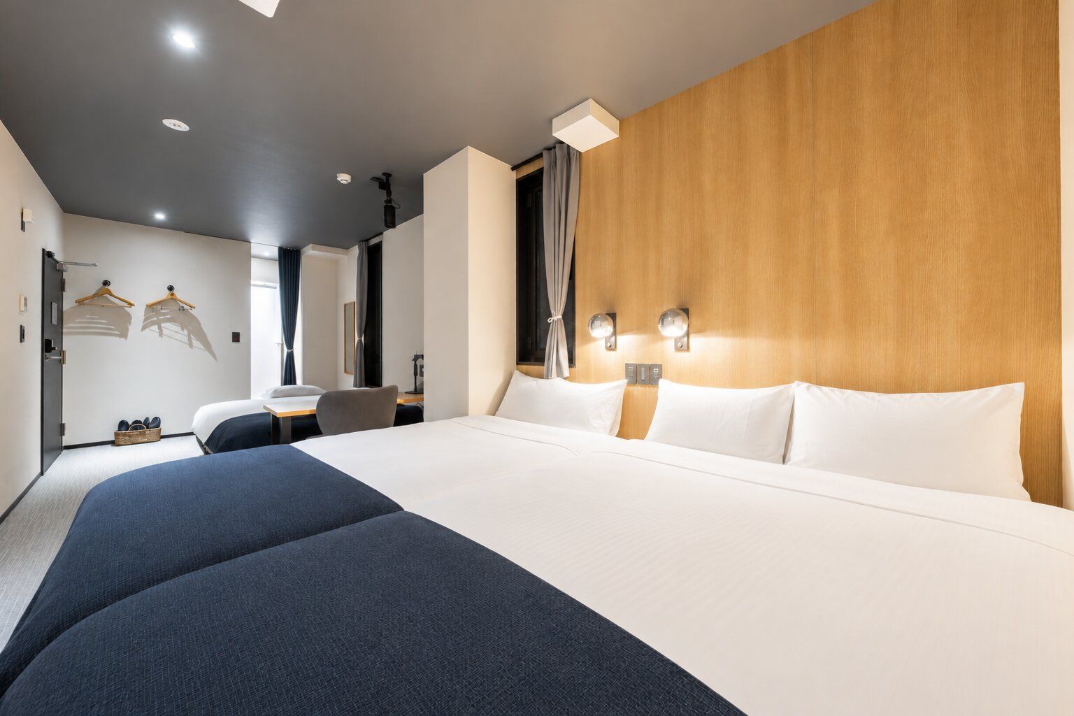 A hotel room with a large bed, a desk, and a wardrobe.