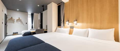A hotel room with a large bed, a desk, and a wardrobe.