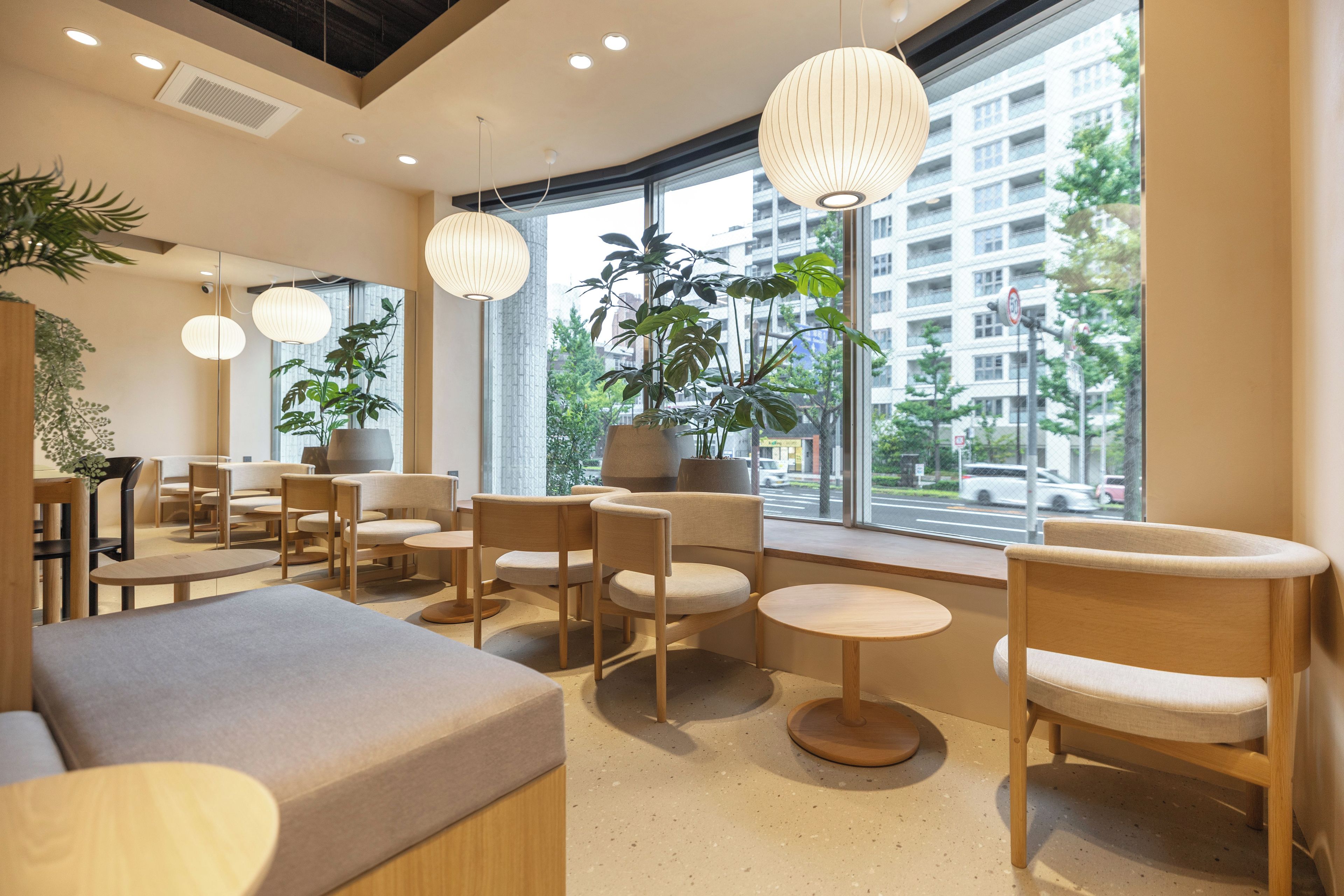 Un intérieur moderne avec des espaces aménagés pour s’asseoir, de grandes fenêtres et des plantes d’intérieur.